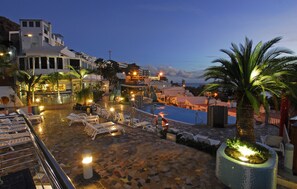 A rooftop pool area with lounge chairs and a palm tree, surrounded by buildings and a view of the sea. - Apartamentos Curasol (Mogan)