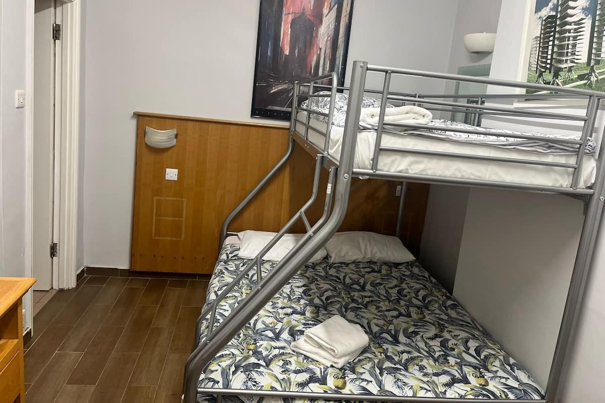 A bunk bed room with a wooden headboard, a painting on the wall, and a window with a view of buildings.