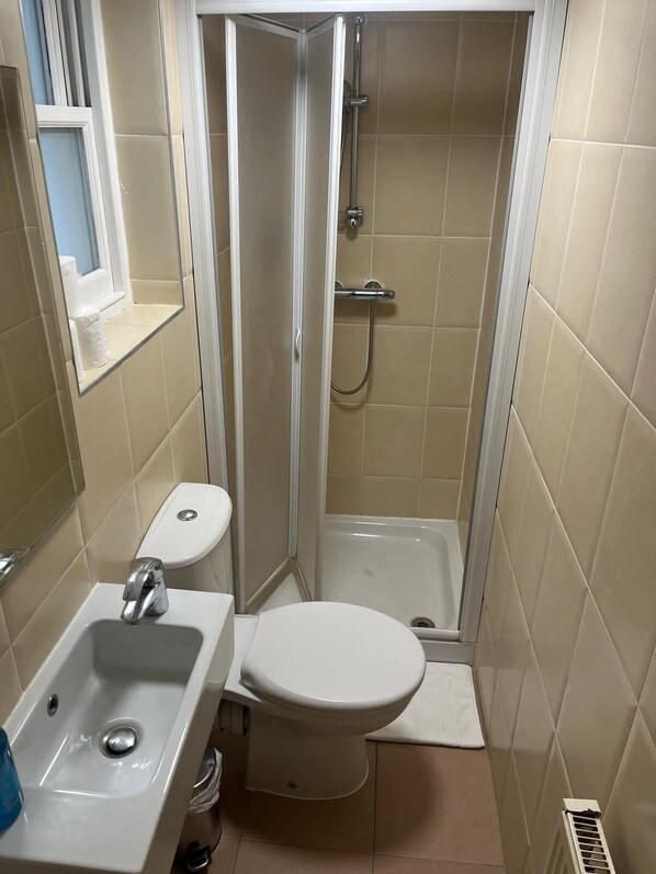 Baño pequeño con inodoro, lavabo y cabina de ducha.