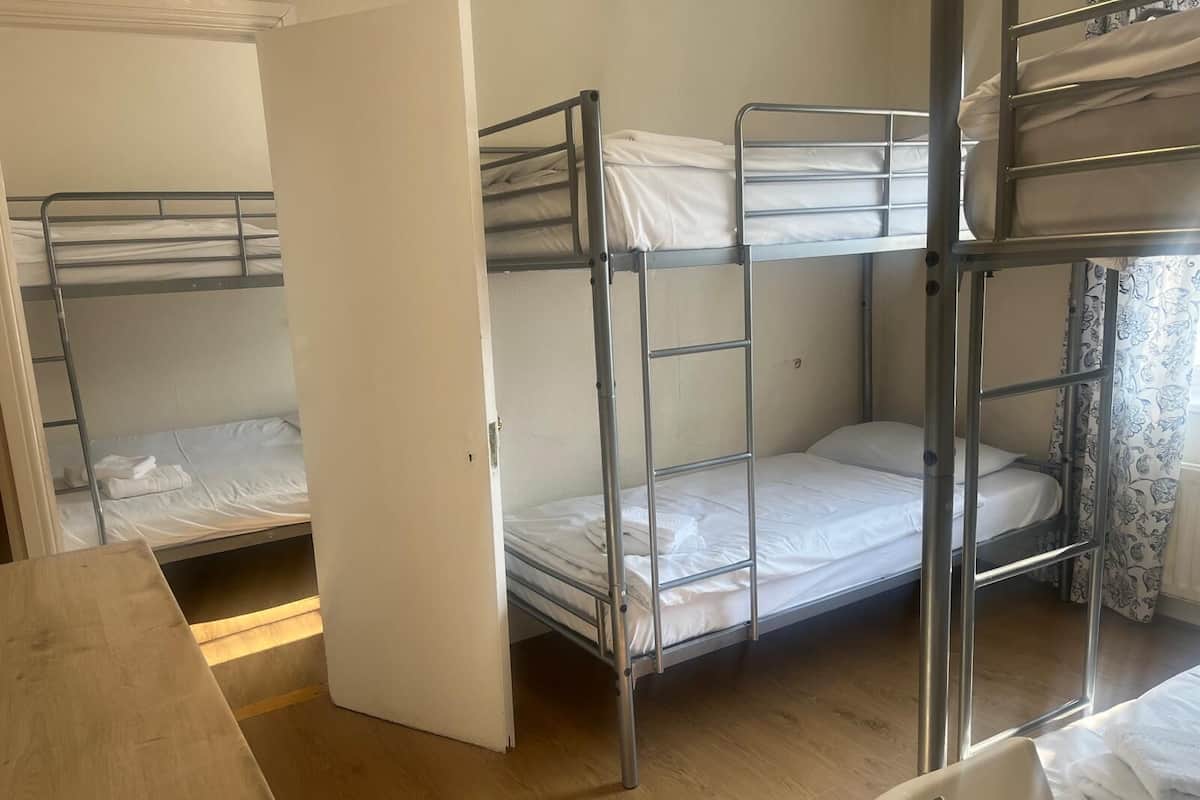 A dormitory room with bunk beds, a wooden table, and a chair.