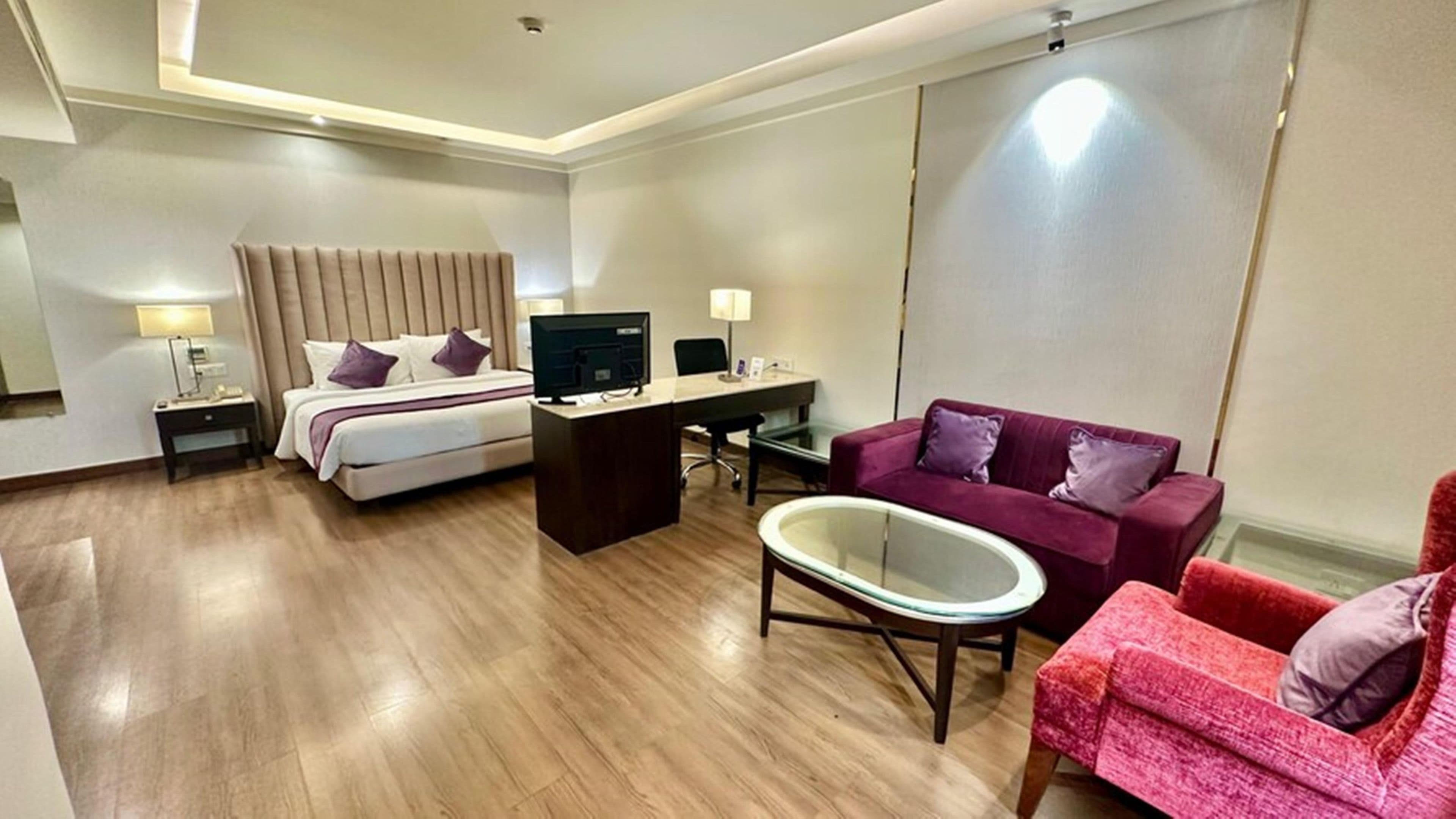 Ein Hotelzimmer mit Bett, Schreibtisch, Computer und zwei Sofas.
