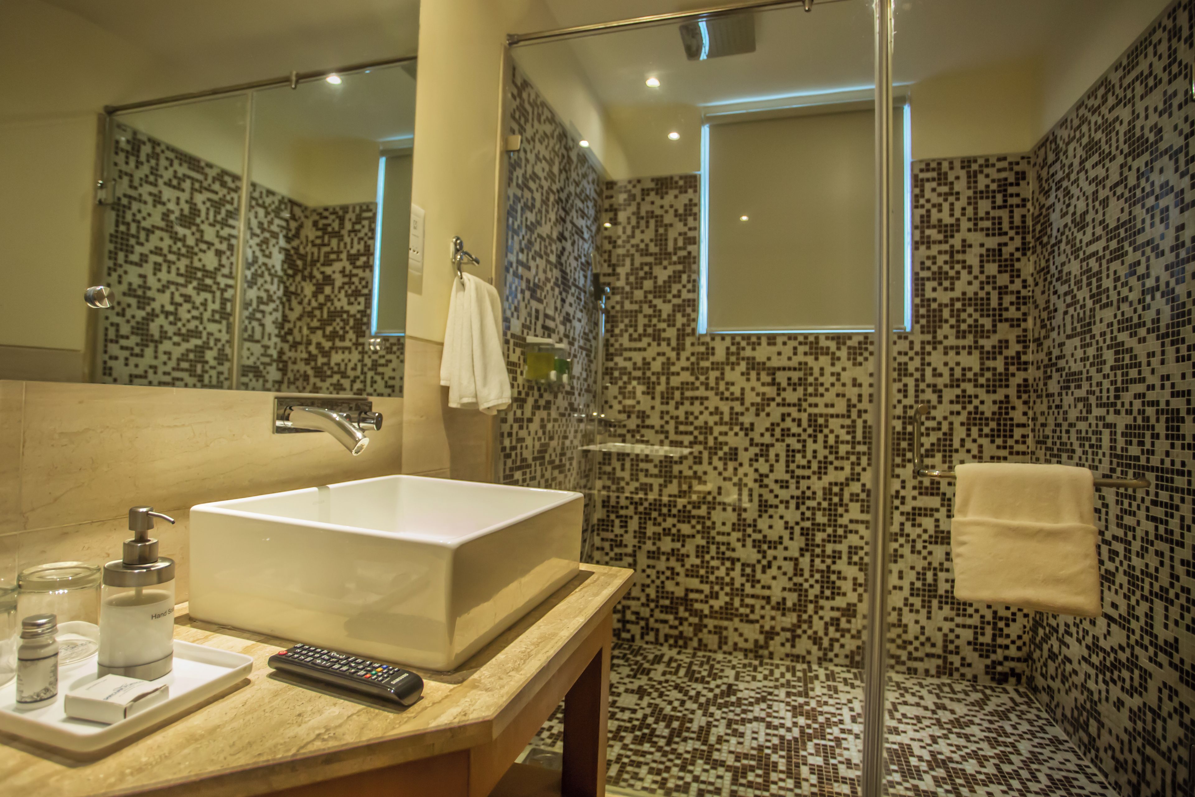 Une salle de bain avec un grand miroir, un lavabo, une douche et un porte-serviettes.