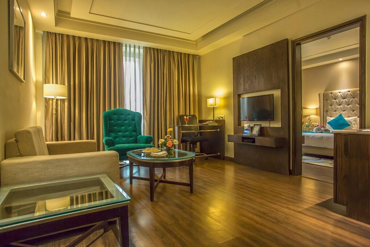 Une chambre d’hôtel comprenant un coin salon, une télévision, un lit et un bureau avec un ordinateur.