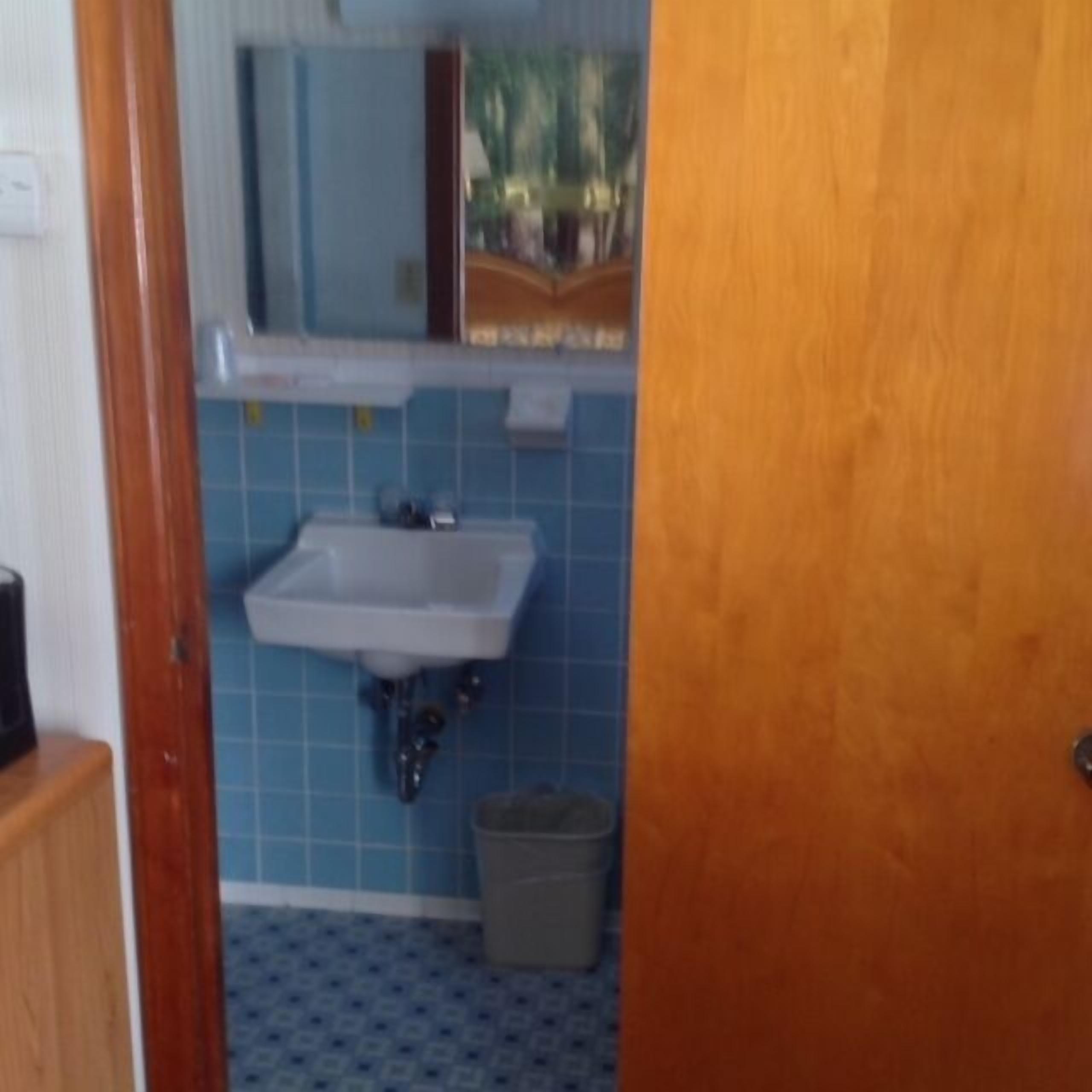 Ein Badezimmer mit Waschbecken, Spiegel und blau gefliestem Boden.