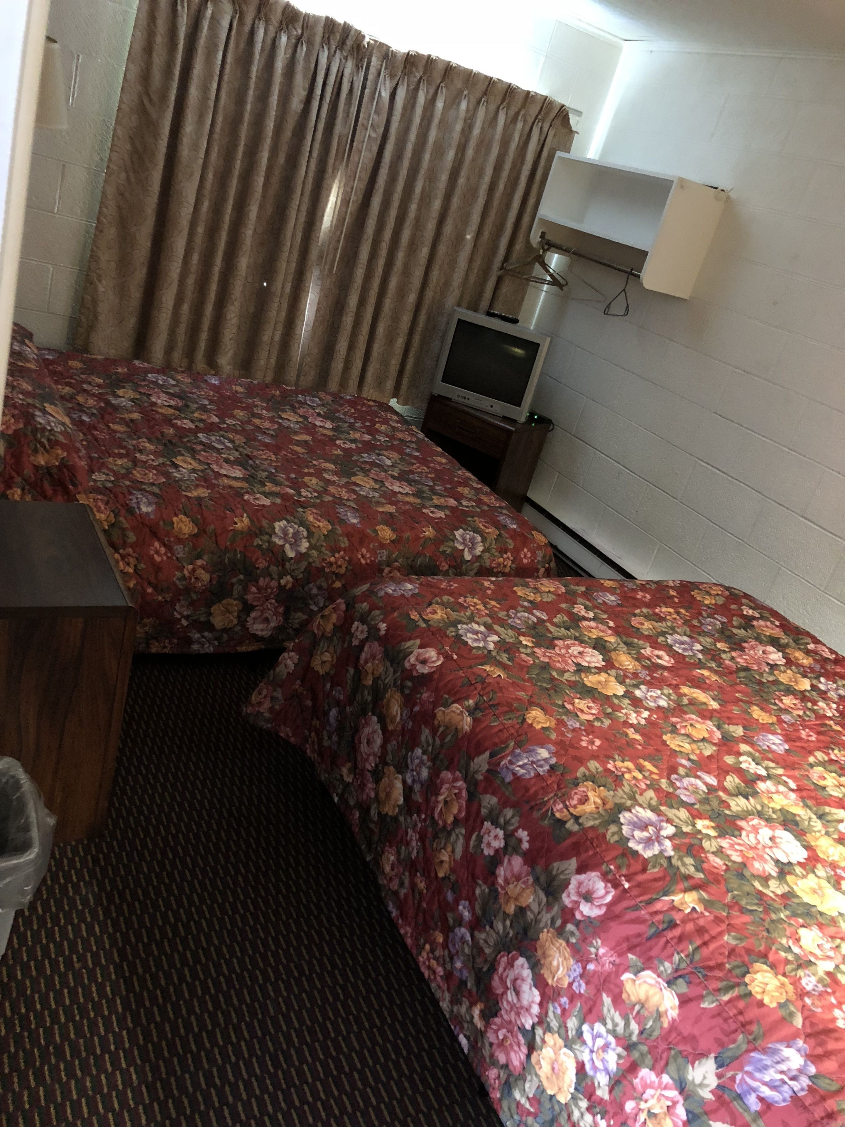 Habitación de hotel con dos camas, un televisor y una lámpara.