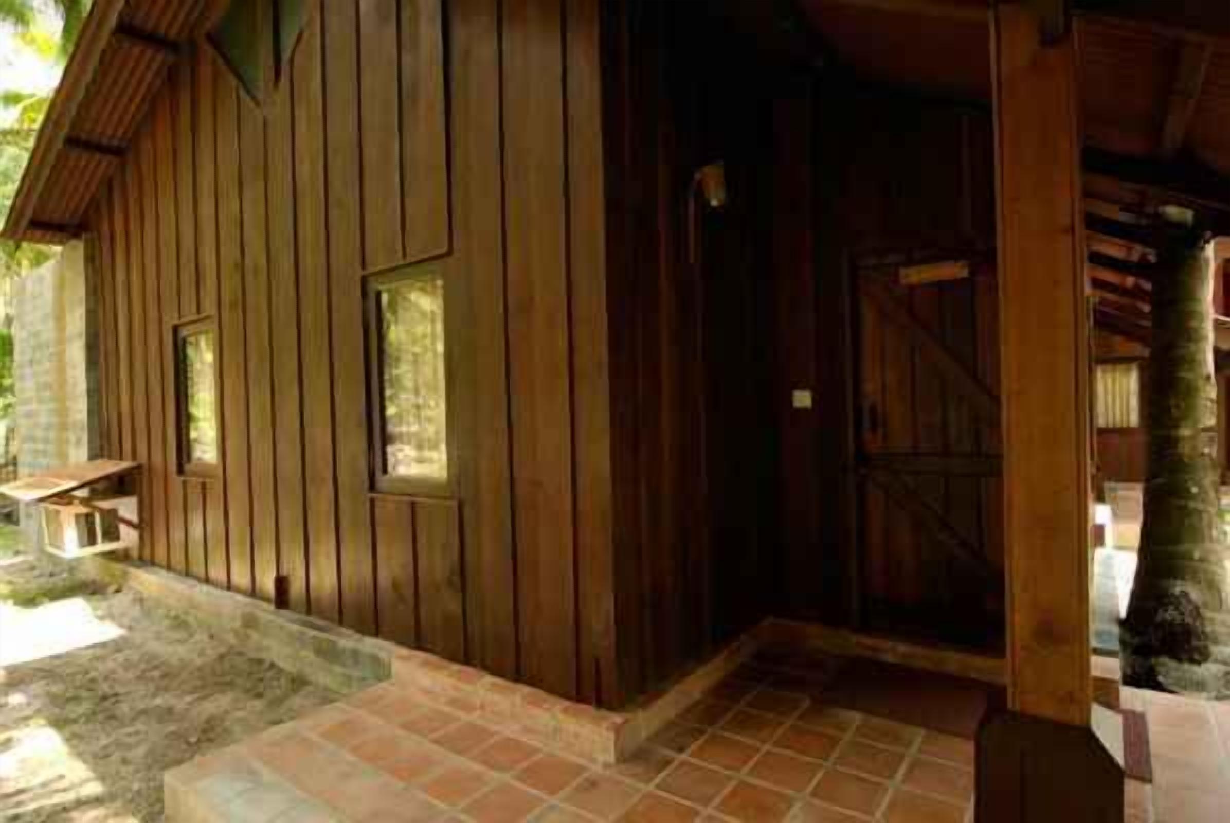 Edificio de madera con zona de entrada enlosetada y una puerta visible.