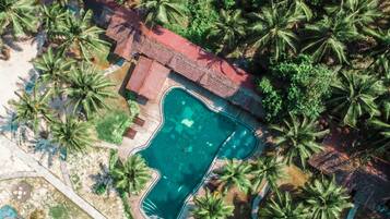 Eine Vogelperspektive auf ein Resort mit einem Swimmingpool, umgeben von Palmen.