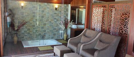 A modern bathroom with a stone wall, a glass shower enclosure, and a wooden ceiling.