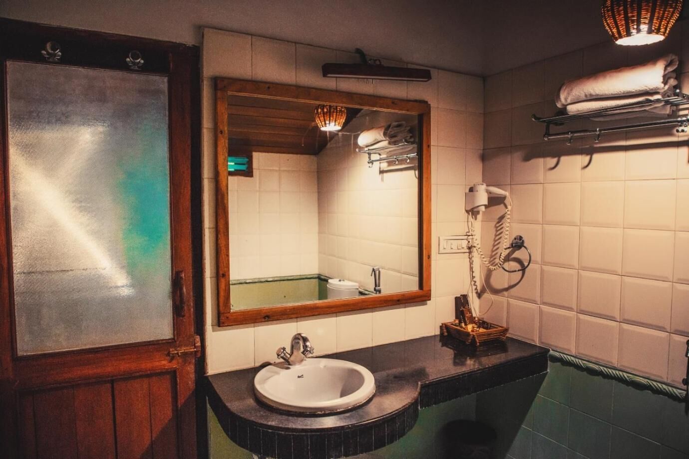 A bathroom with a wooden-framed mirror, a sink, a towel rack, and a hairdryer.