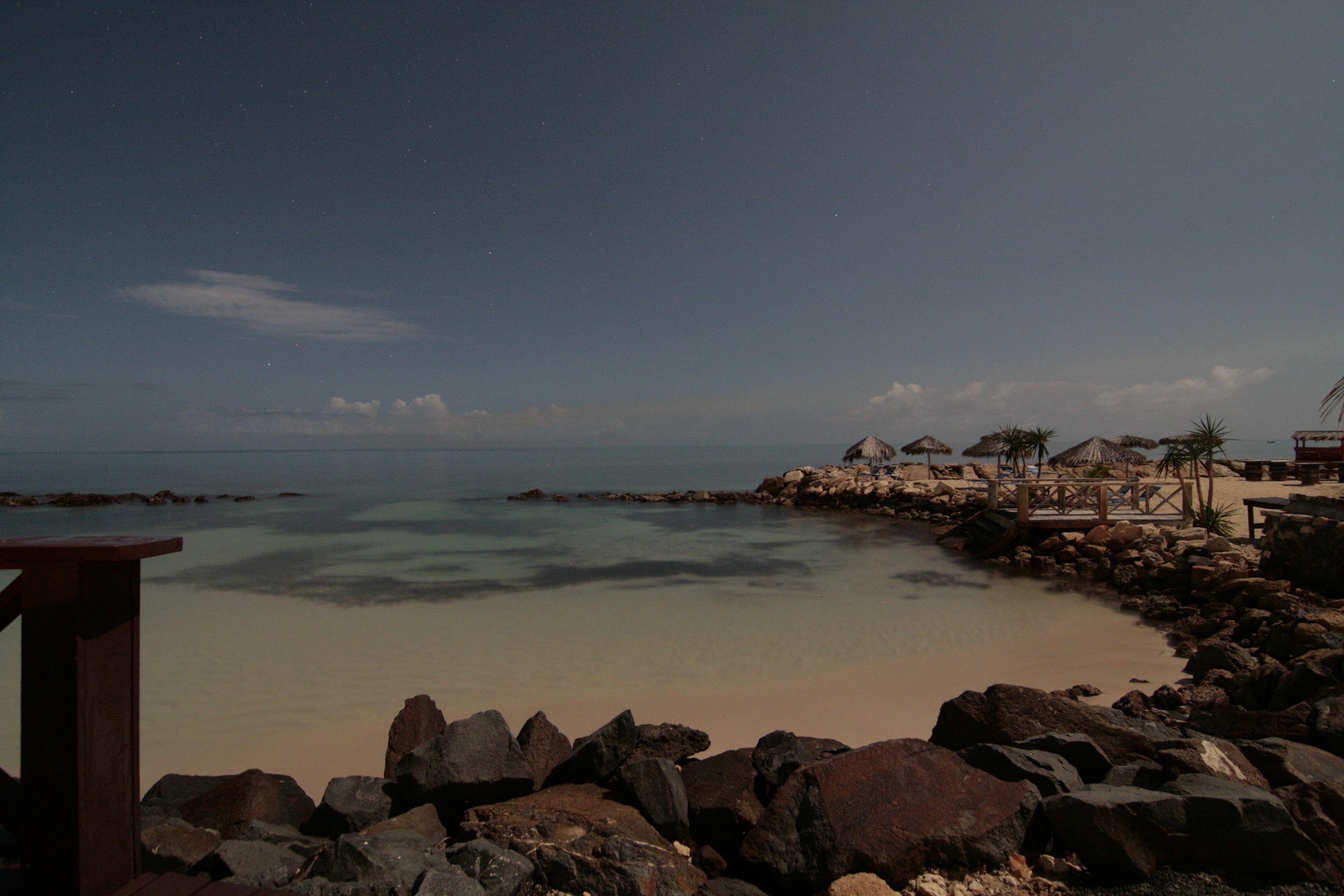 A coastal resort with a rocky shoreline, clear waters, and thatched-roof huts.