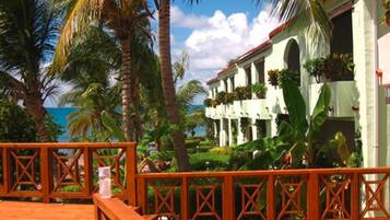 Um hotel à beira-mar com um deque de madeira, palmeiras e vista para o oceano.