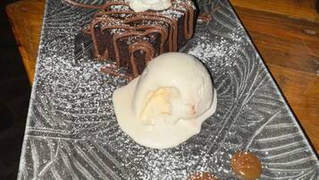 Une assiette à dessert avec un gâteau au chocolat, une boule de glace et deux bonbons ronds.