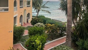 Un hôtel situé sur la côte, avec un palmier, une vue sur la mer et un bâtiment orné d’arcades.