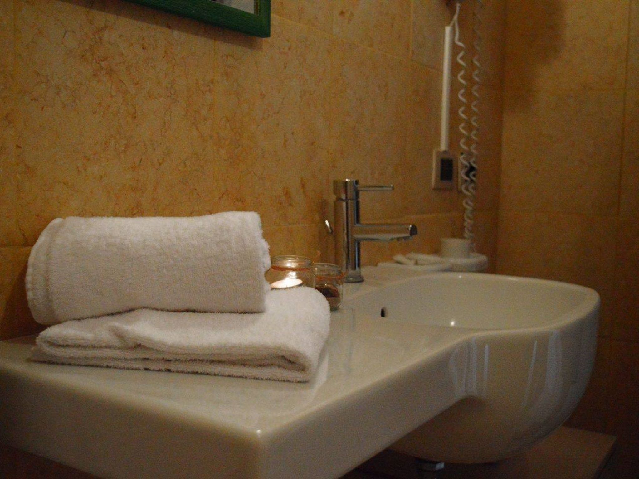 Une salle de bain avec un lavabo, une serviette et une bougie.