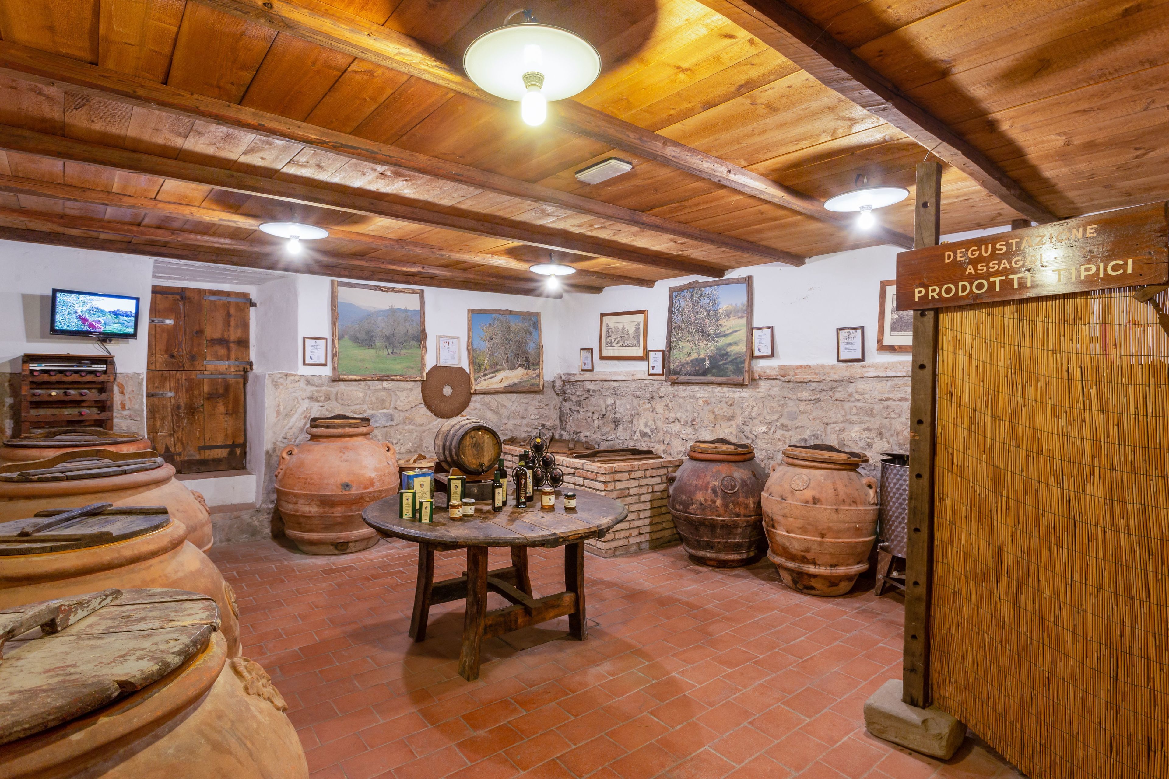 Una bodega rústica con vigas de madera, barriles de terracota y una mesa de madera con botellas.