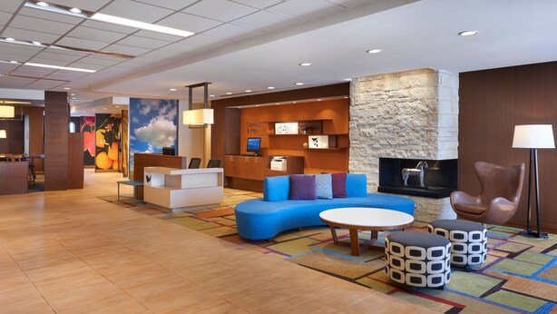 A modern lobby with a blue sofa, a round table, and a stone accent wall. - Fairfield Inn & Suites by Marriott Barrie (Barrie)