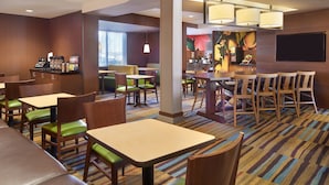 A hotel lobby with multiple seating areas, including tables and chairs, and a bar area with a counter and chairs. - Fairfield Inn & Suites by Marriott Barrie (Barrie)