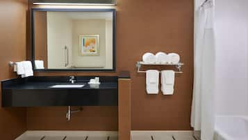 Un baño con lavabo negro, un espejo, un perchero con toallas y una cortina de ducha.