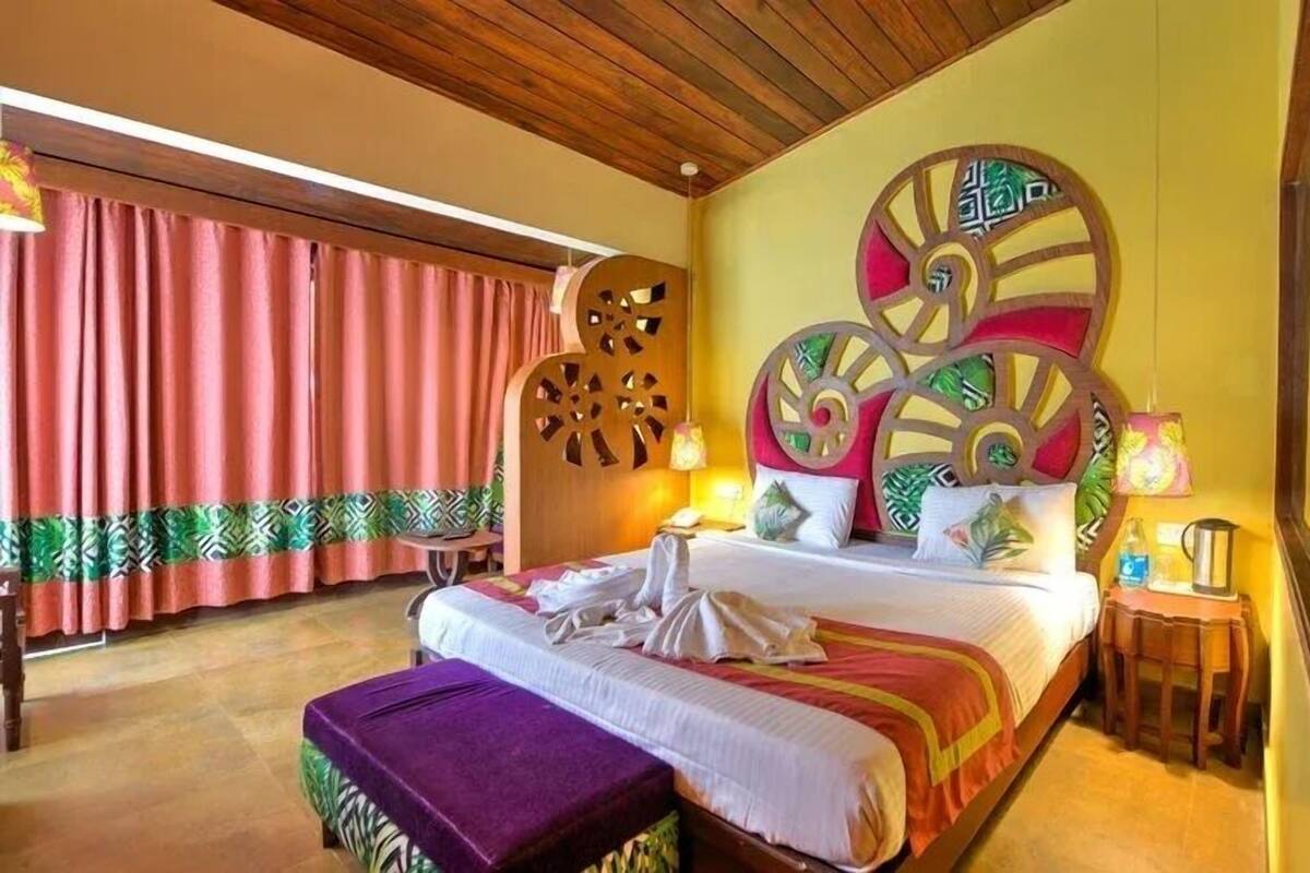 A hotel room with a large bed, a wooden headboard, a small table, and a nightstand.