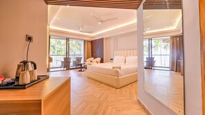 A modern hotel room with a large bed, a desk with a kettle and mugs, and a view of palm trees through the windows. - Silver Sand Sea Princess Beach Resort (Ferrurgunj)