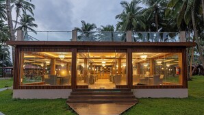 A modern building with glass walls, a staircase leading to the entrance, and a well-lit interior. - Silver Sand Sea Princess Beach Resort (Ferrurgunj)