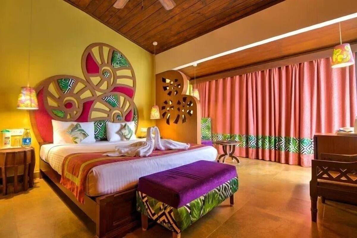 A spacious bedroom with a large bed, a wooden headboard, and a decorative wall panel.