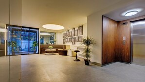 Eine moderne Lobby mit Empfangstresen, Sitzgelegenheiten und einem Aufzug.