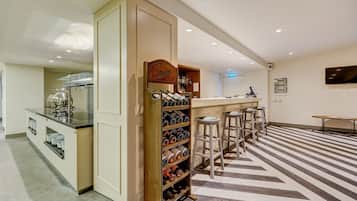Una cocina moderna con una estantería para vinos, taburetes de bar y una encimera con una cafetera.