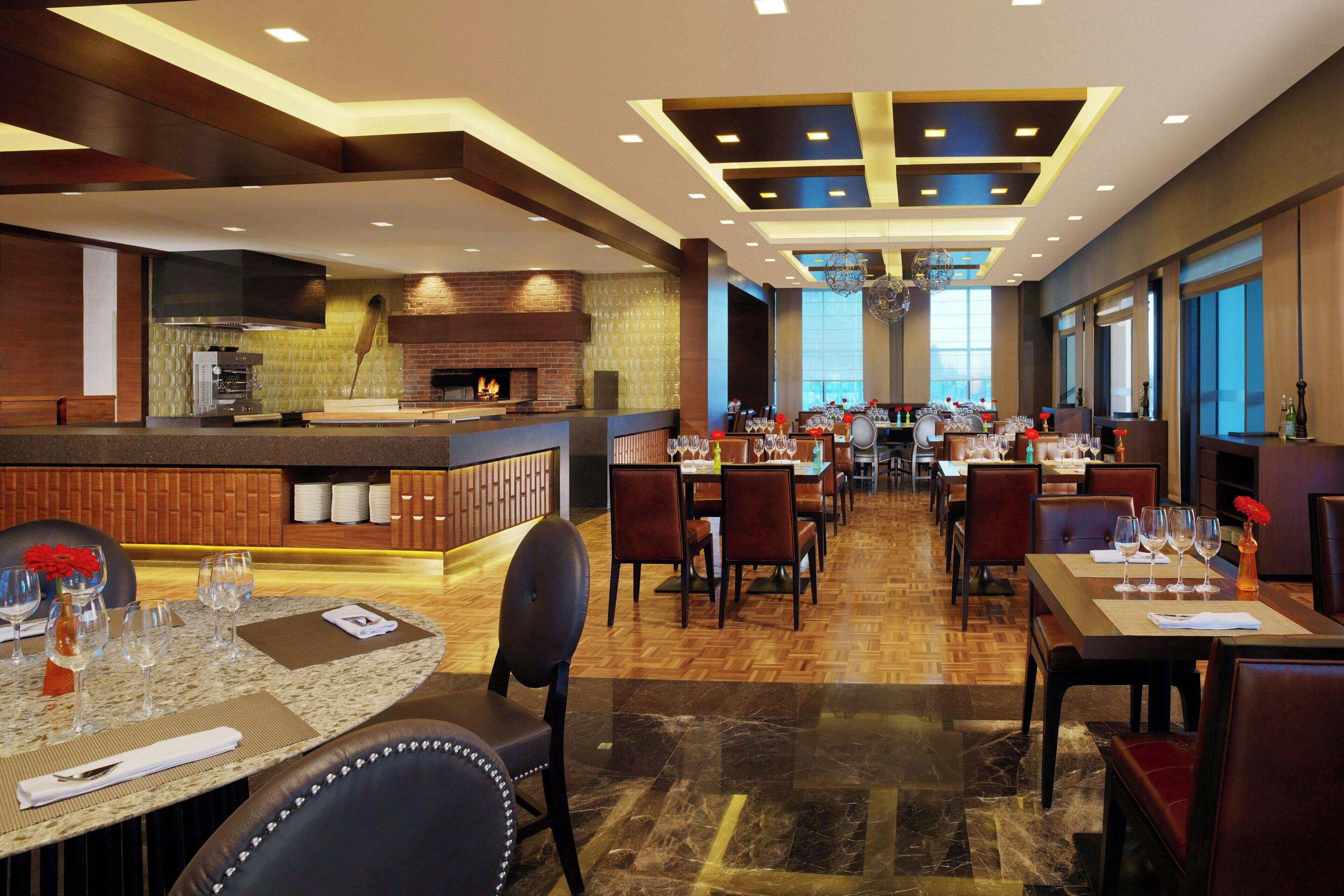 A spacious restaurant with a central bar, multiple dining tables, and a modern interior design.