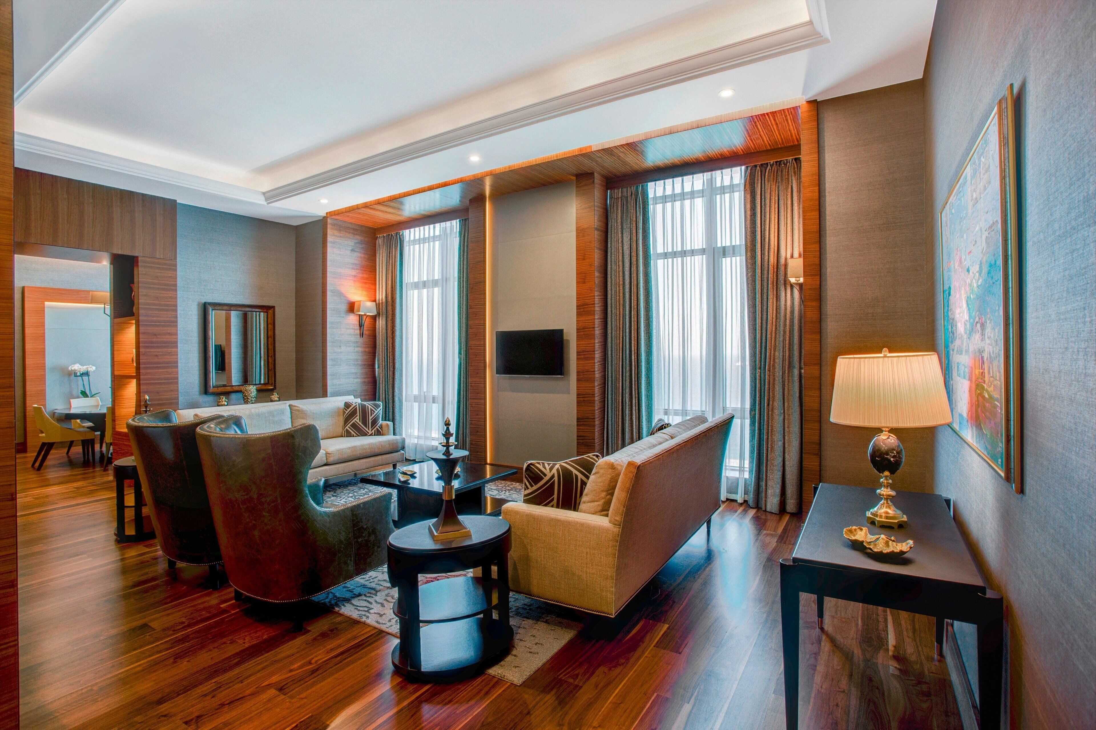 A modern living room with a sofa, armchairs, a coffee table, and a TV.