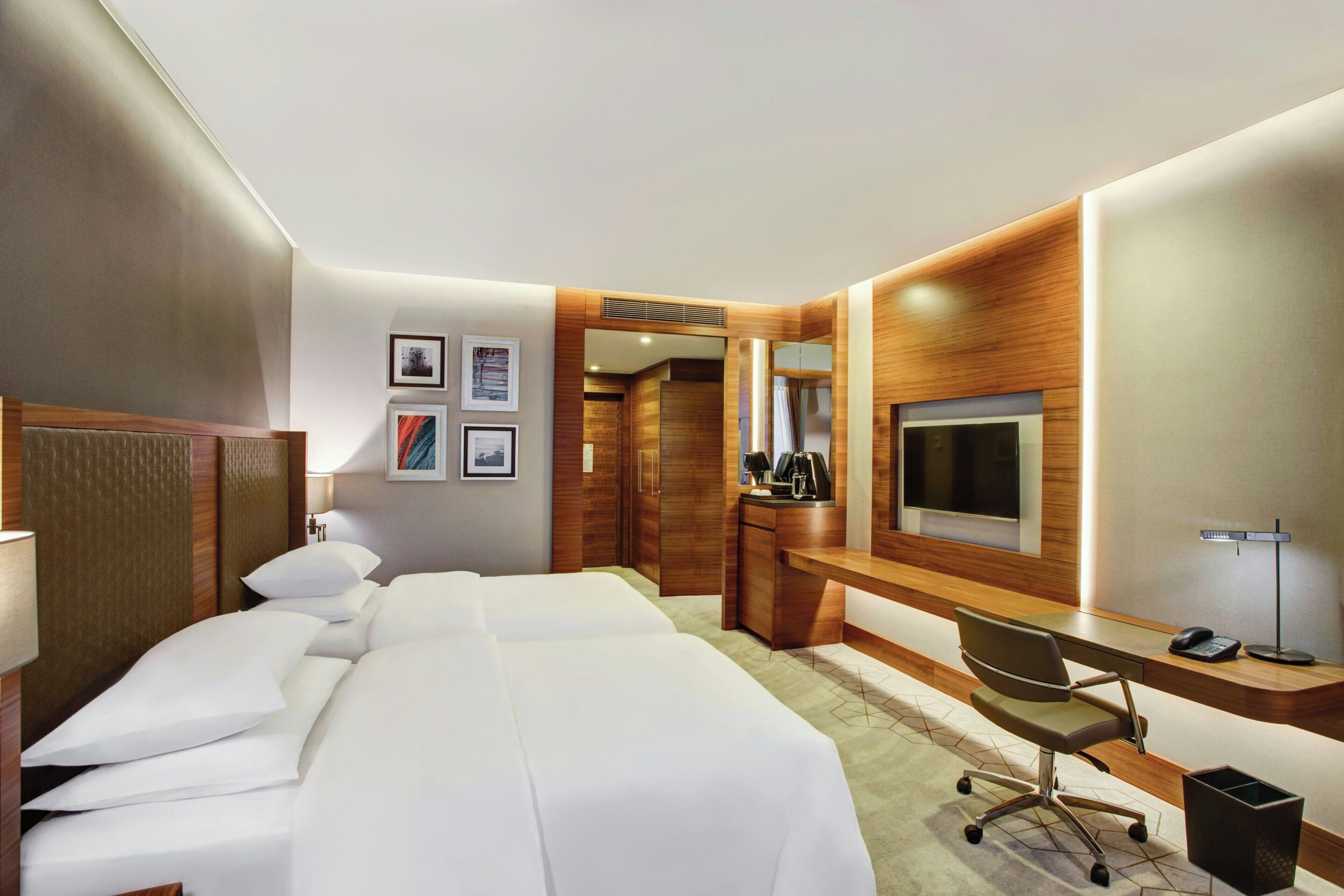 A hotel room with a bed, a desk, a chair, a TV, and a coffee maker.