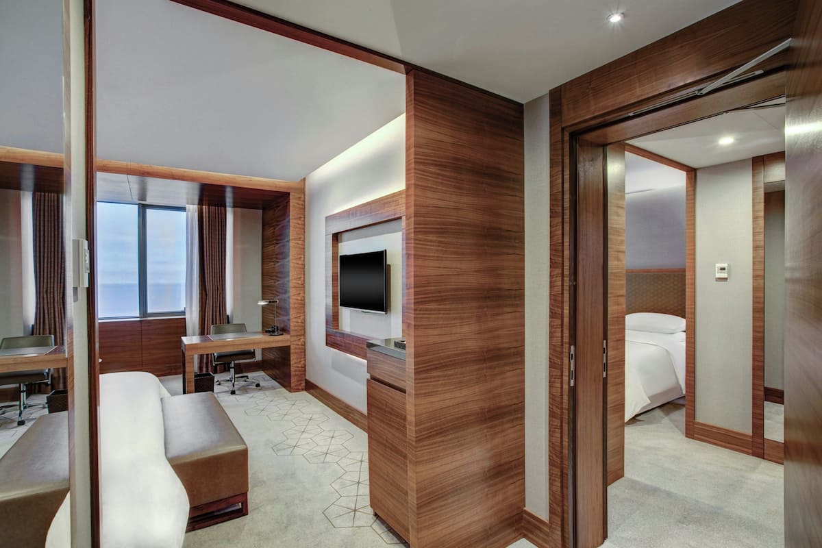 Una habitación de hotel moderna con una cama grande, un escritorio, un televisor y un baño con ducha e inodoro.