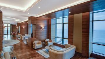 A spacious living area with a large window offering a view of the sea, wooden flooring, and modern furniture.