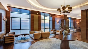 Un hall d’entrée spacieux, doté d’une grande fenêtre offrant une vue sur le ciel, d’une table ronde centrale et d’un mobilier moderne.