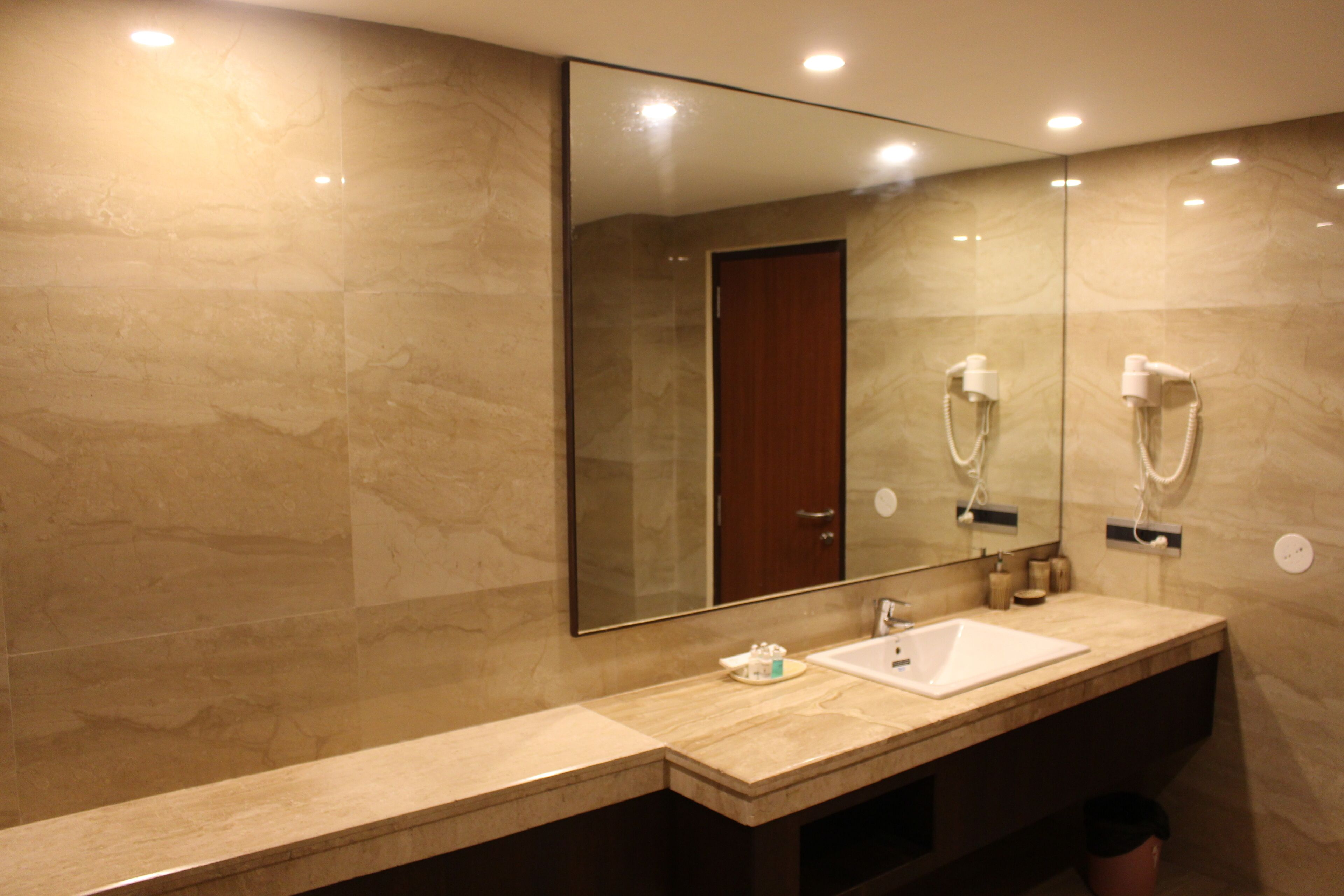 A modern bathroom with a large mirror, two sinks, and a hairdryer.