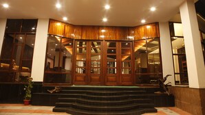 Fachada de hotel de madera, puertas de cristal y una escalera que conduce a la entrada.