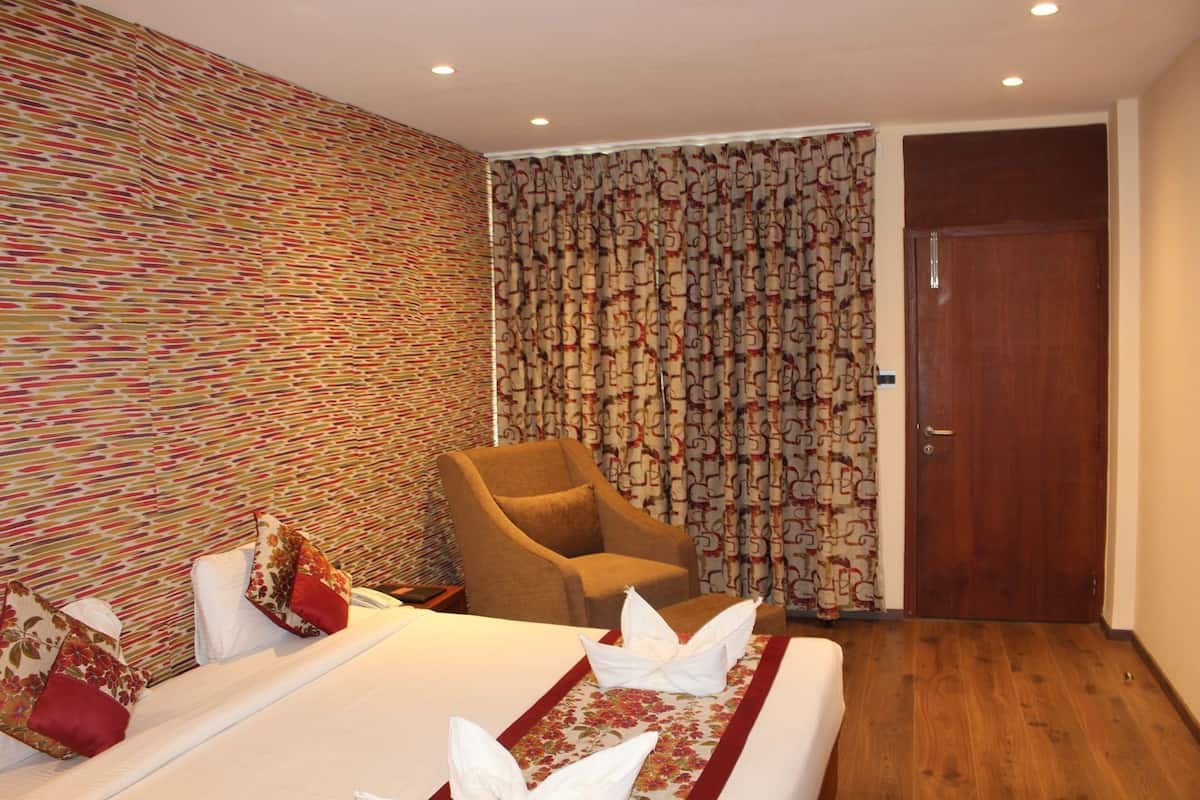 A hotel room with a bed, a chair, a patterned wall, and a door.
