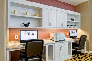 A workspace with two desks, each with a computer and a printer. There are white cabinets above the desks and a patterned floor. - Hampton Inn & Suites Cincinnati-Downtown (Cincinnati)
