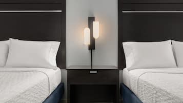 Habitación de hotel con dos camas, una mesita de noche y una lámpara fijada a la pared.