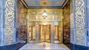 A grand entrance with ornate gold detailing, a chandelier, and a sign reading 'ENQUIRER'.