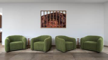 A room with three green armchairs, a white wall, and a framed picture.