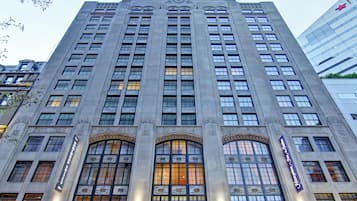 A tall, multi-story building with a classical architectural style, featuring a central entrance with arched windows and a prominent sign above.