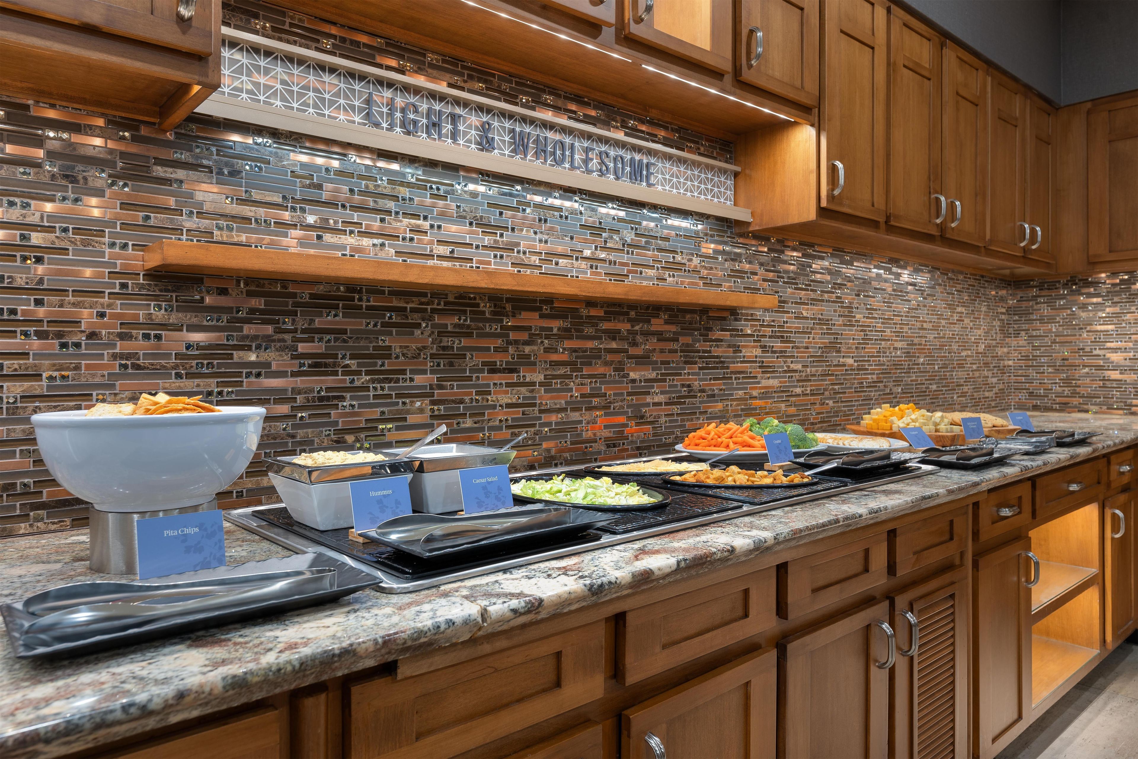 A buffet setup with various food items and serving utensils.