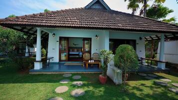 A traditional house with a tiled roof, a porch with seating, and a garden with stepping stones.