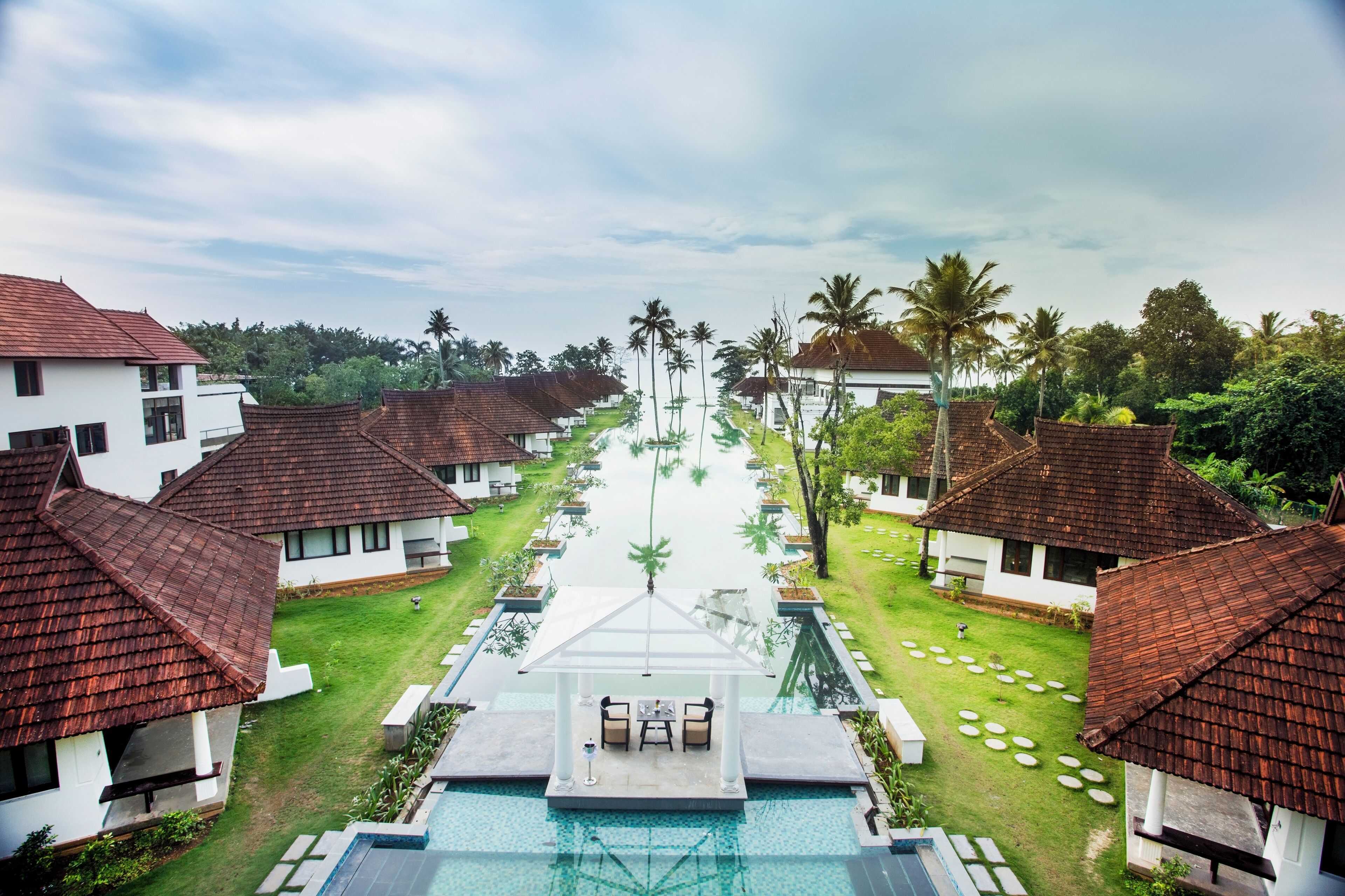 A resort with multiple bungalow-style buildings, a central swimming pool, and a well-maintained lawn.