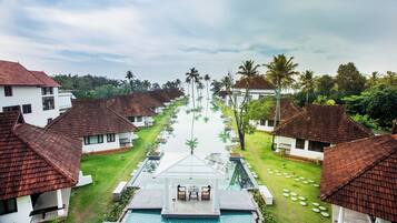 A resort with multiple bungalow-style buildings, a central swimming pool, and a well-maintained lawn.