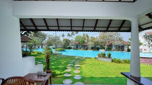 Un patio techado con vista a una piscina, muebles de exterior y un césped bien cuidado.