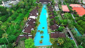 Un resort con piscina central, rodeado de exuberante follaje y palmeras.