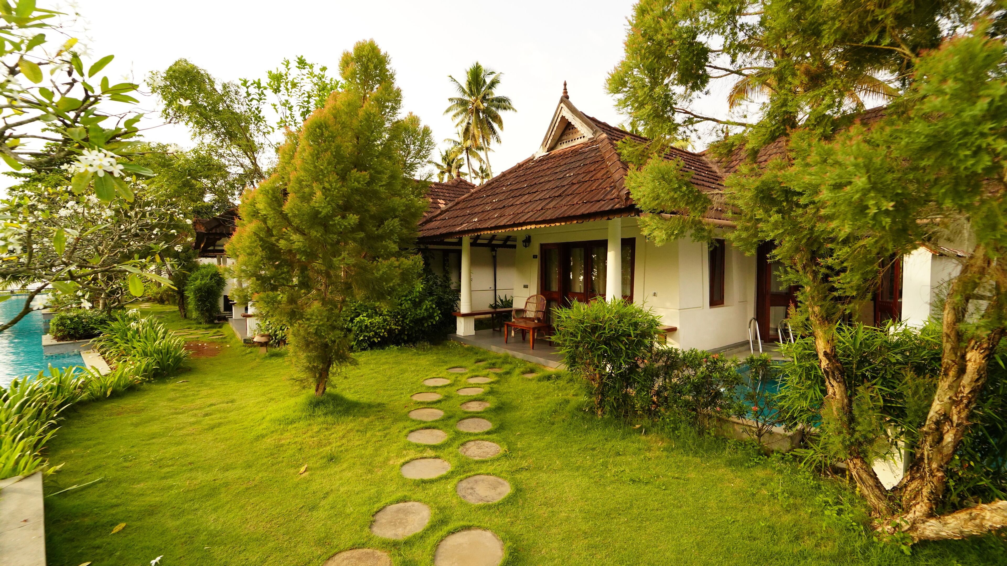 A house with a tiled roof, a garden with a circular stepping path, and a pool.
