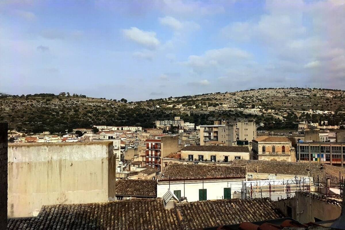 Un paisaje urbano con edificios, una colina al fondo y un cielo despejado.